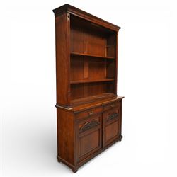 Late Victorian tall walnut open bookcase on cupboard, projecting cavetto cornice over reeded and fluted uprights moulded with roundel motifs, flanking two adjustable shelves, the base fitted with two drawers over panelled cupboards, carved with oakleaf and acorn motifs and grapevines, on bracket feet