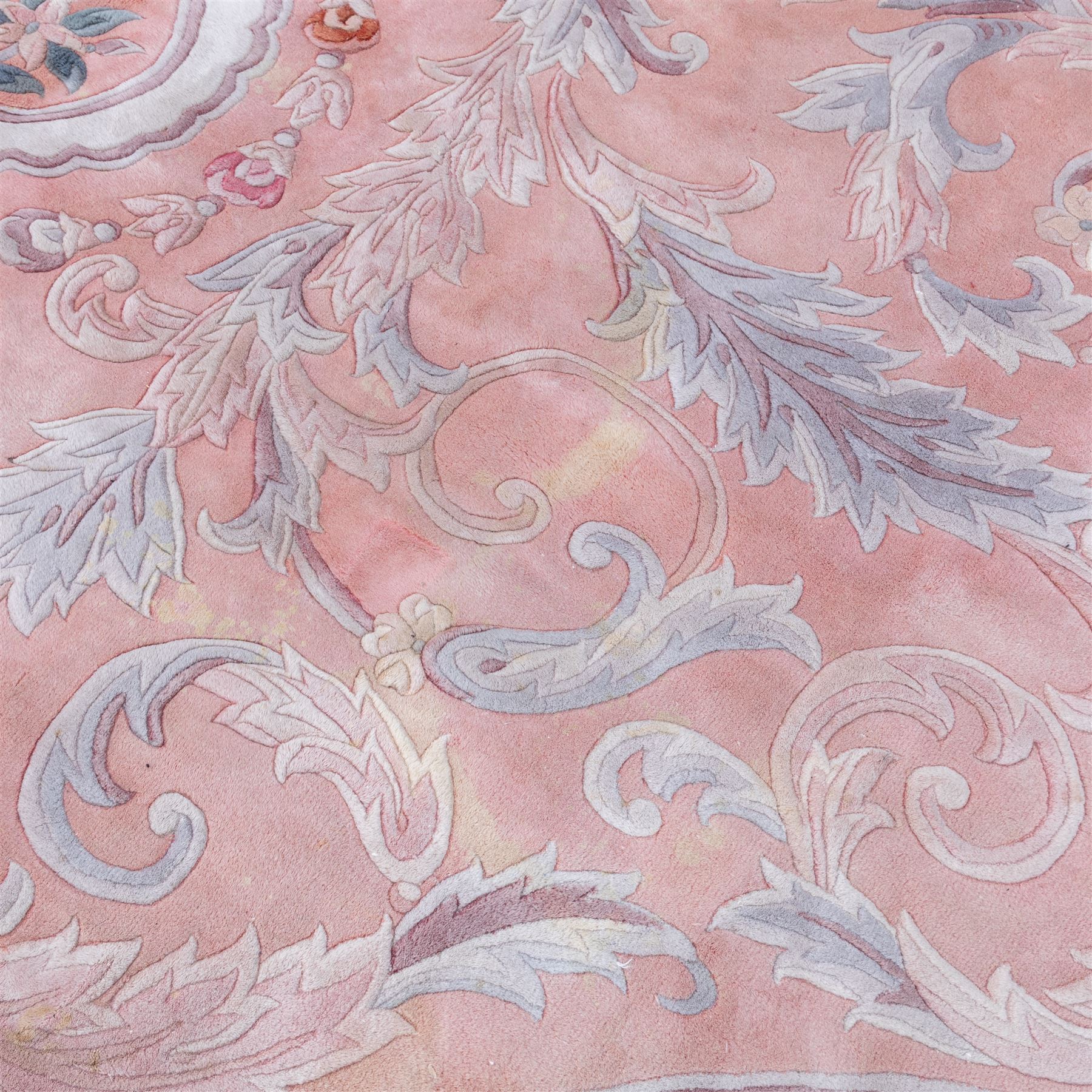 Large late 20th century Aubusson style wool carpet, peach and pastel toned field with central floral medallion enclosing scrolling acanthus and and foliate sprays, surrounding field decorated with further stylized foliage and and floral ornament, within shaped reserves and indigo corner spandrels, enclosed by narrow guard border, cotton fringe ends