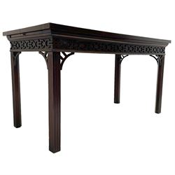 In the manner of Thomas Chippendale - early 19th century mahogany serving table, rectangular crossbanded top with boxwood stringing, the frieze with upper moulding over applied geometric fretwork, the left-hand side fitted with slide, on fluted square supports with inner chamfer 