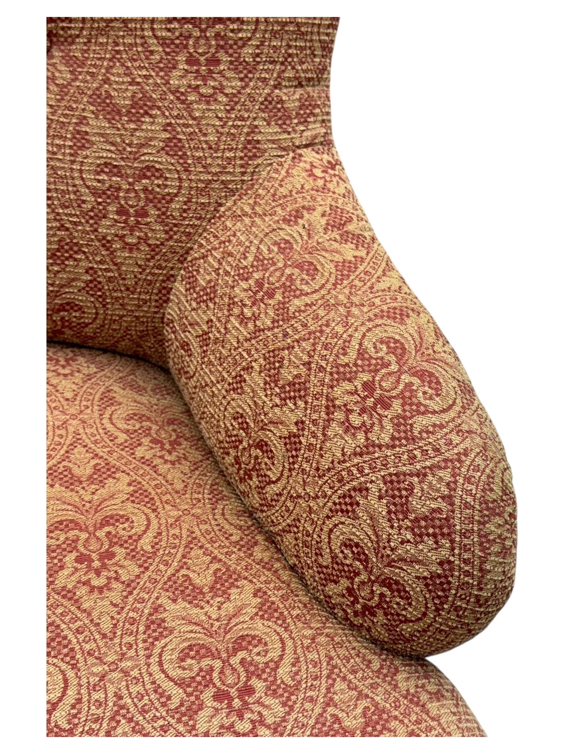 Late Victorian upholstered armchair, with high camel back and deep seat, padded arms and backrest in crimson and cream damask-style fabric, raised on turned ebonised front supports with ceramic castors (H88cm, W65cm, D 60m); and an Edwardian bedroom chair with button upholstered rail back (H72cm, D64cm, W53cm) (2)