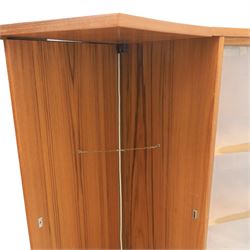 Turnidge of London - Mid 20th century teak drinks cabinet, shaped top with hinged fold-out side sections, twin doors with recessed handles enclosing fitted shelving and serving surfaces, sliding glass doors to the back, on a plinth base above castors