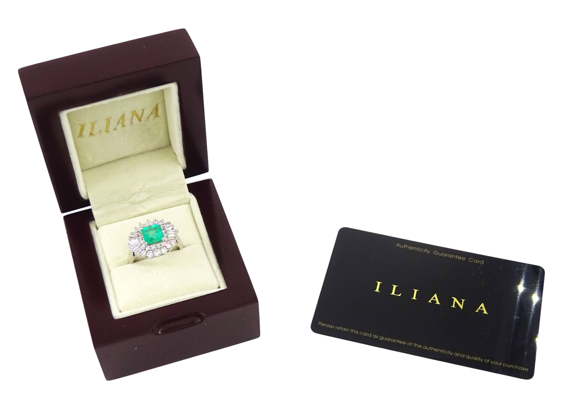 18ct white gold Colombian emerald and diamond cluster ring by Iliana, single octagonal cut emerald of 1.65 carat, surrounded by two rows of round brilliant cut and tapered baguette cut diamonds, hallmarked