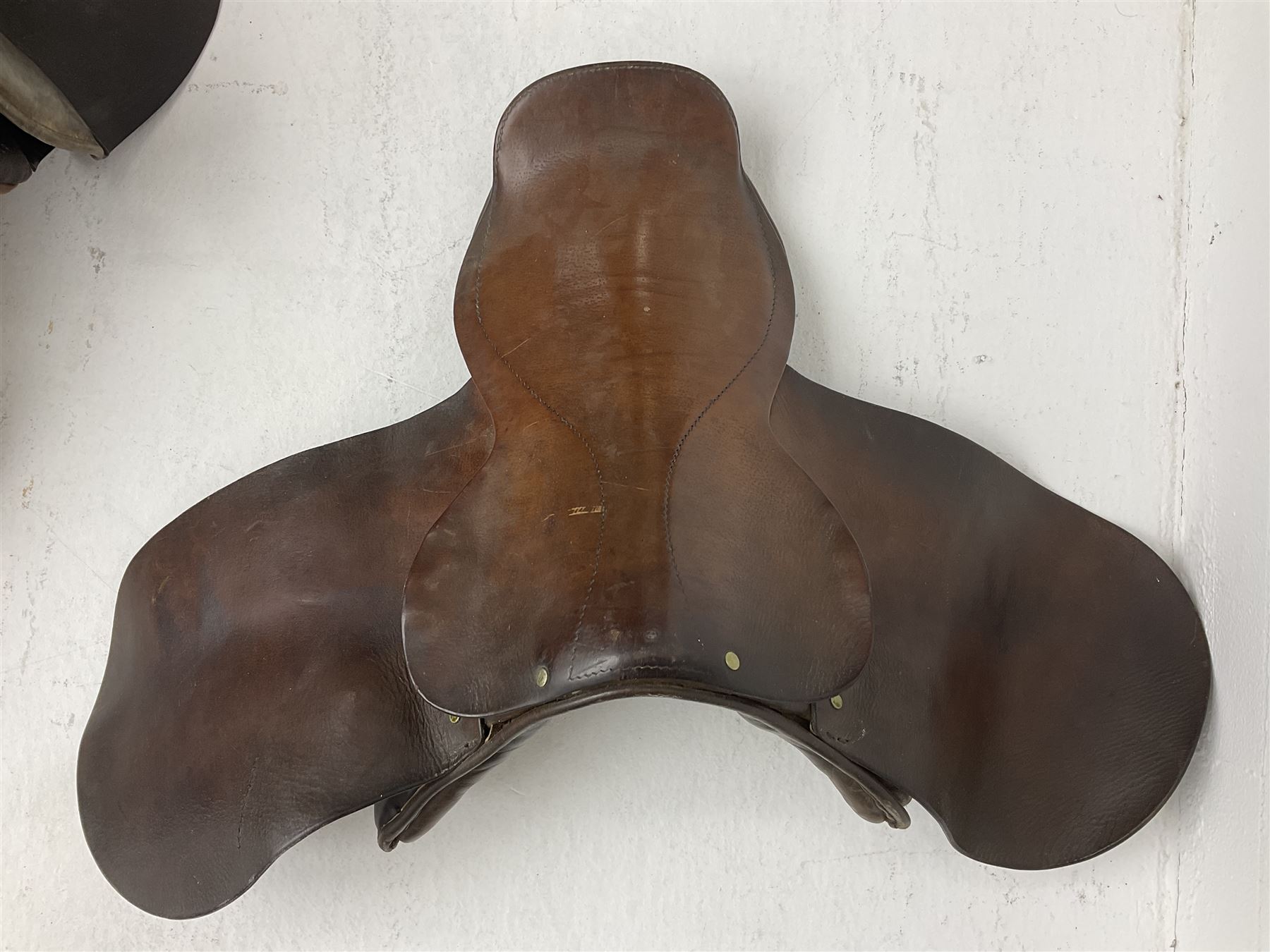 Collection of nine saddles, mainly havana leather to include a racing saddle and a Goodwin saddle, some with stirrups and leathers 