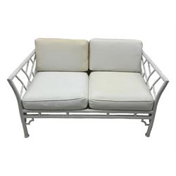 Late 20th century faux bamboo conservatory sofa, white painted frame with geometric openwork back and sides, loose cream cushions, on cylindrical supports (W134cm, D76cm, H80cm); matching armchair (W75cm, D76cm, H80cm); matching coffee table with glass insert (W46cm, D45cm, H36cm)