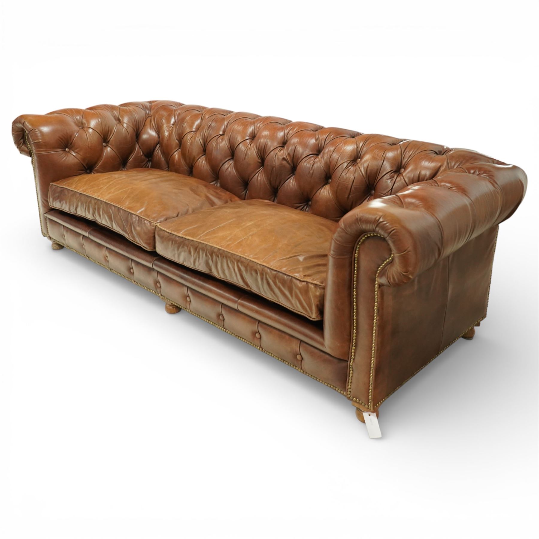 Timothy Oulton for Halo - three seat chesterfield sofa, deep button tufted back and arms in tan leather, loose seat cushions, studded detail to the scrolled arms and lower frieze, raised on turned bun feet