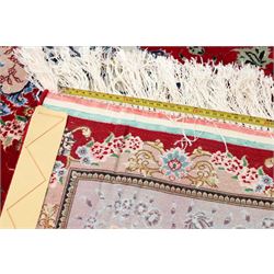 Fine Persian silk inlaid crimson ground Tabriz rug, the shaped field decorated with a central foliate pole medallion filled and surrounded by finely knotted floral motifs and trailing foliage, the cyan guard stripe with bold festoons and palmette motifs