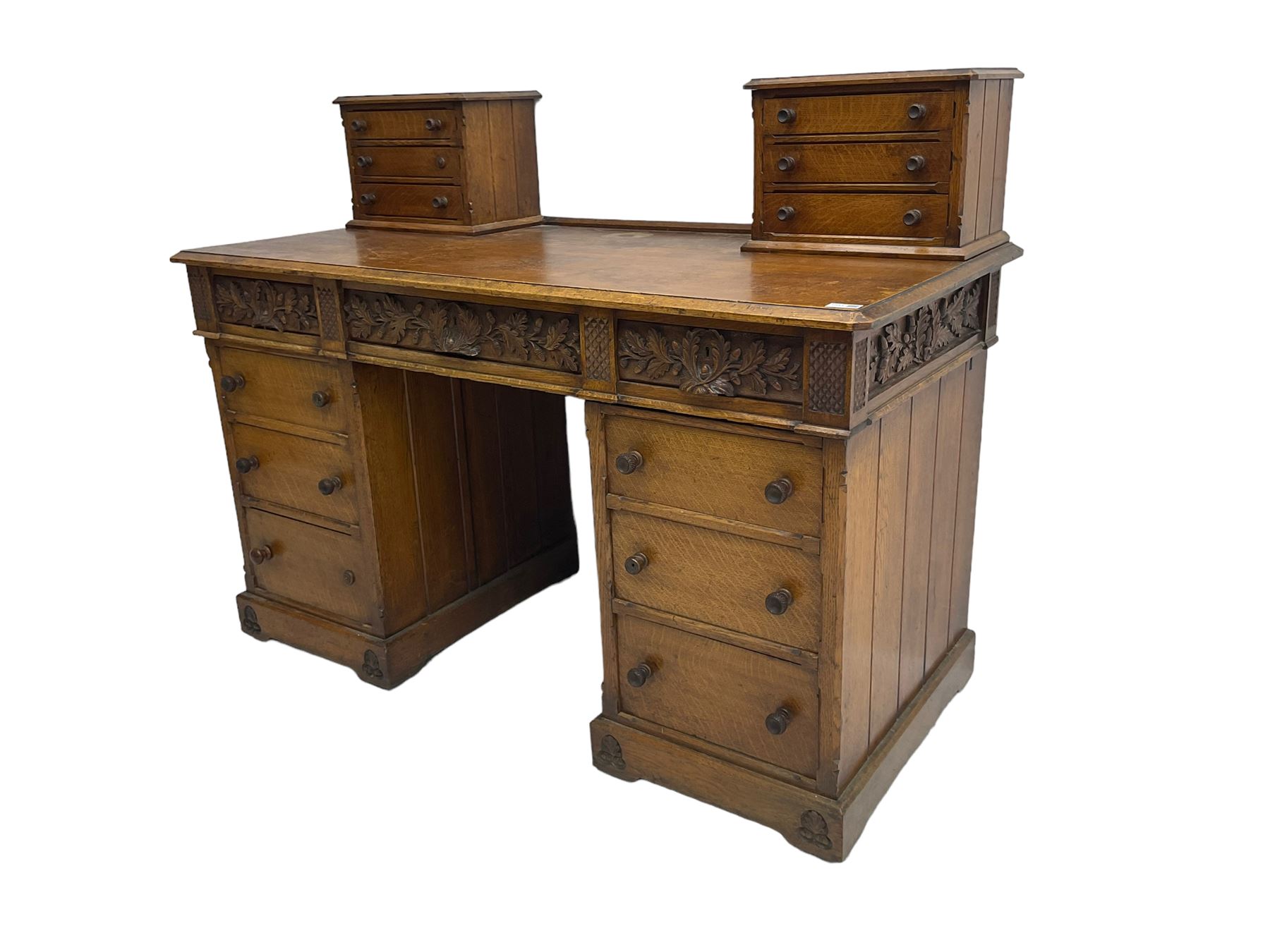 Late 19th century heavily carved oak twin pedestal desk, rectangular top with two raised trinket or correspondence structures each with three drawers, rectangular top over three frieze drawers carved with acorn and oak leaf decoration, each pedestal with three drawers with acorn husk shaped handles