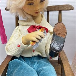 Anna Meszaros Hungary - three hand made needlework figurines - 'The Cobbler' as a child seated in a wooden rocking chair working on a removed boot H28cm; young girl in a long floral dress standing playing a harp H35cm; and young girl wearing a blue tabard standing playing a lute (3) Auctioneer's Note: Anna Meszaros came to England from her native Hungary in 1959 to marry an English businessman she met while demonstrating her art at the 1958 Brussels Exhibition. Shortly before she left for England she was awarded the title of Folk Artist Master by the Hungarian Government. Anna was a gifted painter of mainly portraits and sculptress before starting to make her figurines which are completely hand made and unique, each with a character and expression of its own. The hands, feet and face are sculptured by layering the material and pulling the features into place with needle and thread. She died in Hull in 1998.  