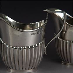 Victorian silver two piece bachelors tea service, comprising teapot and milk jug, of oval part fluted form, the teapot with ebonised wooden handle and finial, hallmarked Josiah Williams & Co, London 1895, together with a silver milk jug and open sucrier, of similar form, hallmarked William Hutton & Sons, London 1898