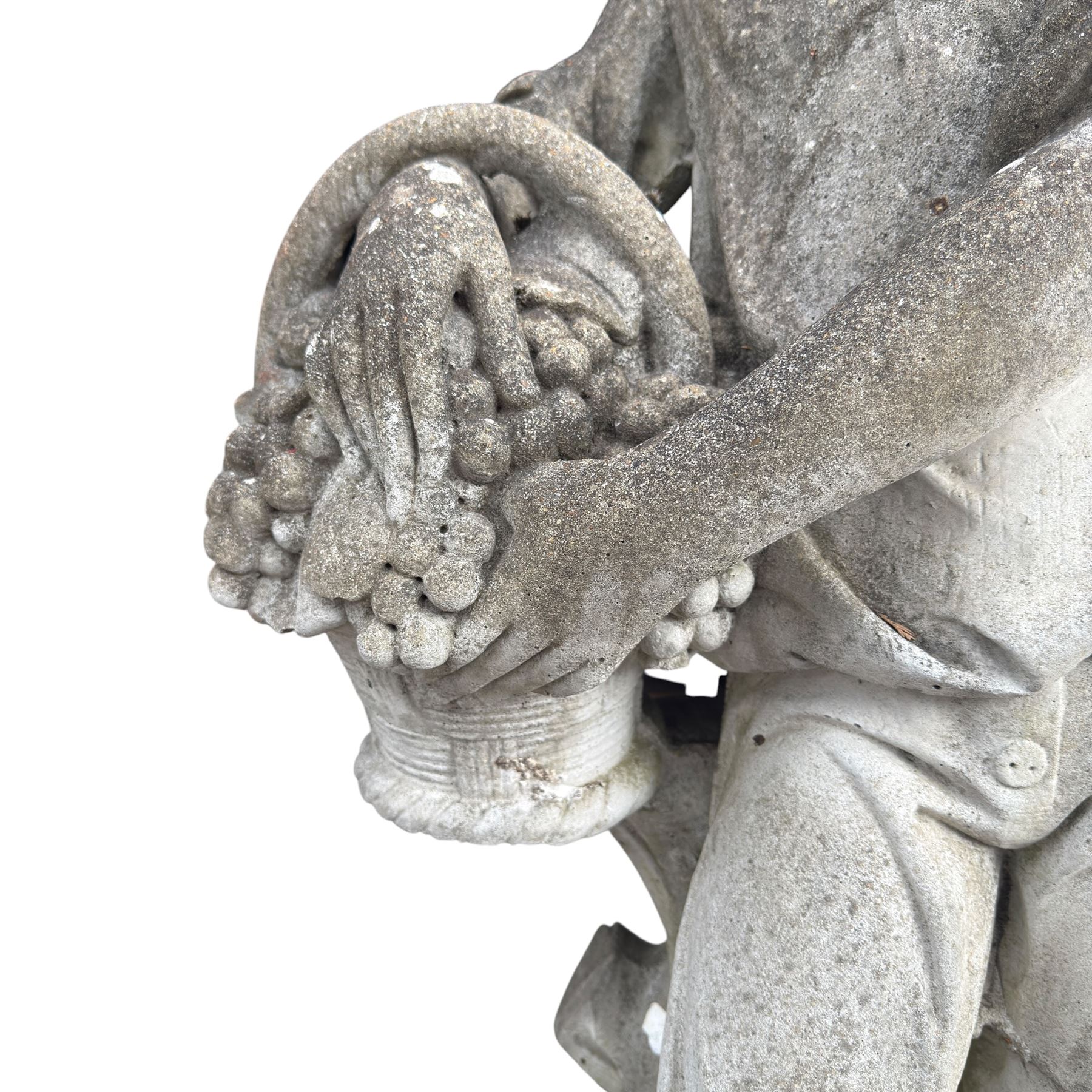 Haddonstone - weathered cast stone garden statue of a boy holding a basket of grapes, modelled with curled locks of hair wearing a tunic and breeches leaning against a naturalistic tree stump, on square base