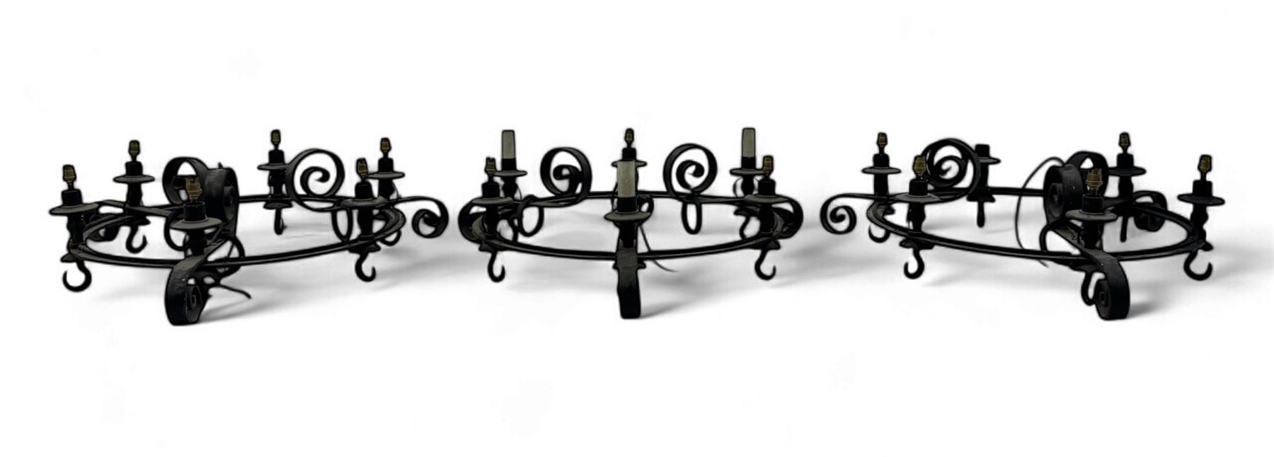 Set of three mid-20th century wrought iron six-light chandeliers, each with a circular frame with scrolled arms, faux candle sleeves and hook terminals
