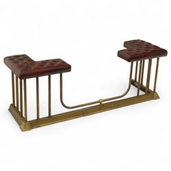 Late Victorian brass and cast iron club fender, burgundy leather buttoned seat pads, secured by bar uprights at the front and back, and a cross stretcher held in place by further bar uprights on a chamfered platform base, circa 1890, internal base dimensions 127cm 