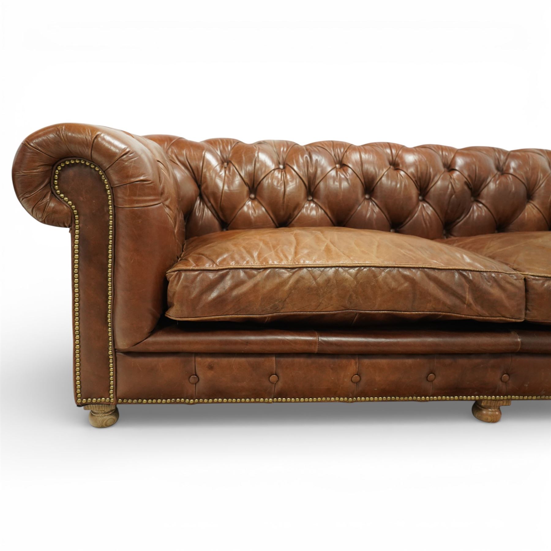 Timothy Oulton for Halo - three seat chesterfield sofa, deep button tufted back and arms in tan leather, loose seat cushions, studded detail to the scrolled arms and lower frieze, raised on turned bun feet