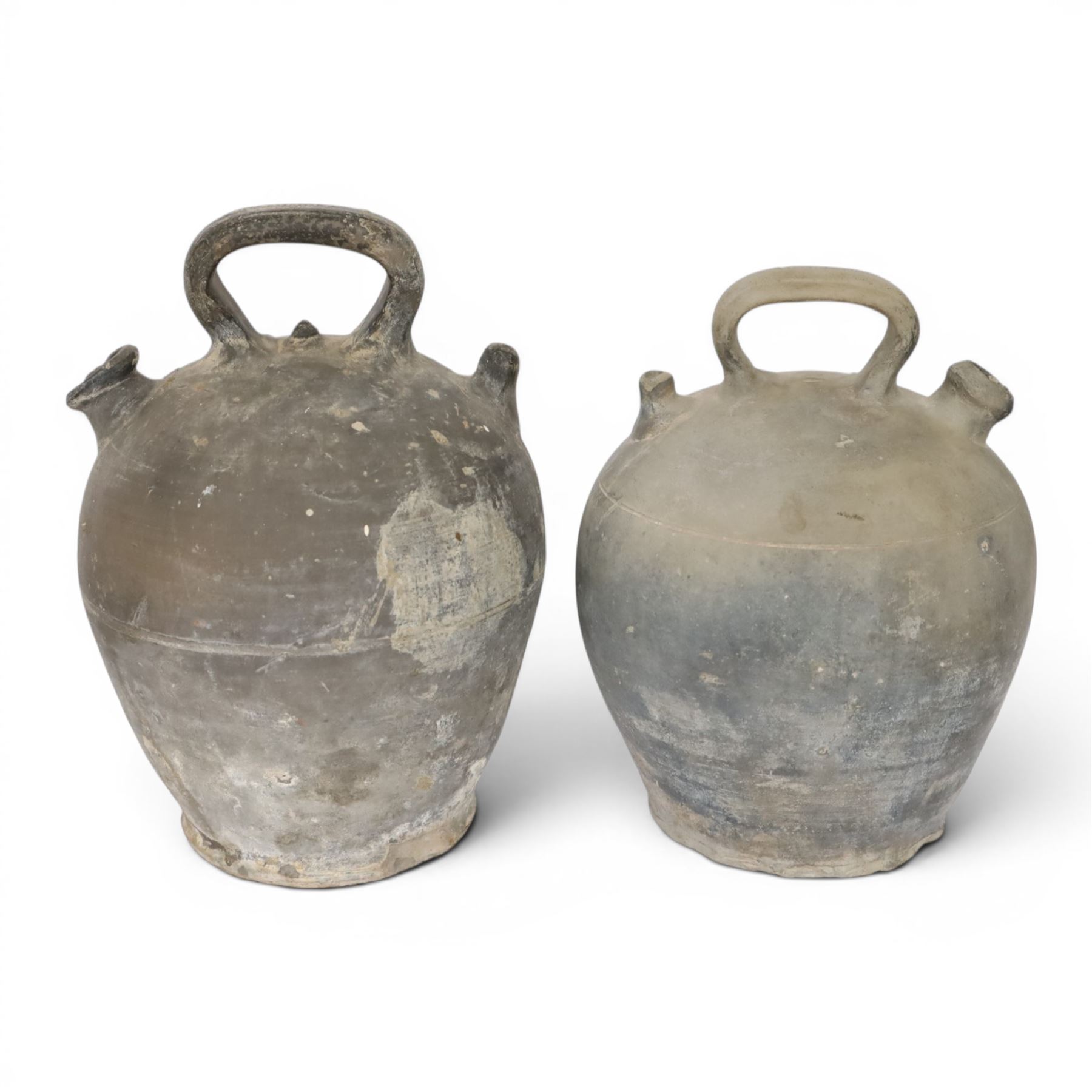 Four 20th century Spanish blackened earthenware botijo or cruche vessels, each of typical baluster form with central loop handle and opposing spout, impressed marks to handles, tallest example H31cm