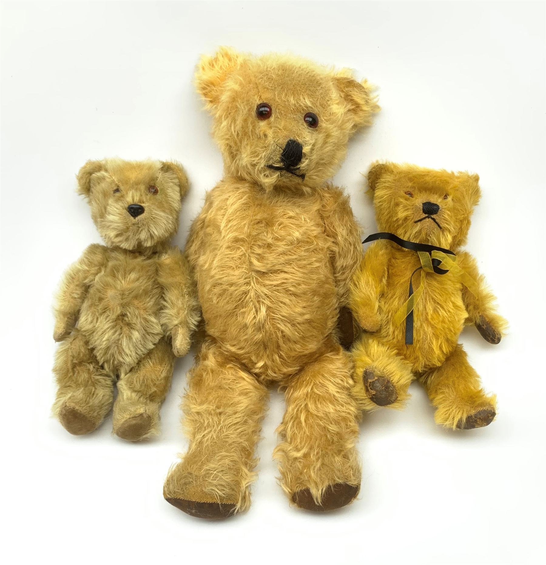 Three English teddy bears c1930s-50s comprising Chiltern wood wool filled Hugmee flat faced bear with swivel jointed head, vertically stitched nose and mouth and jointed limbs with rexine paw pads H12