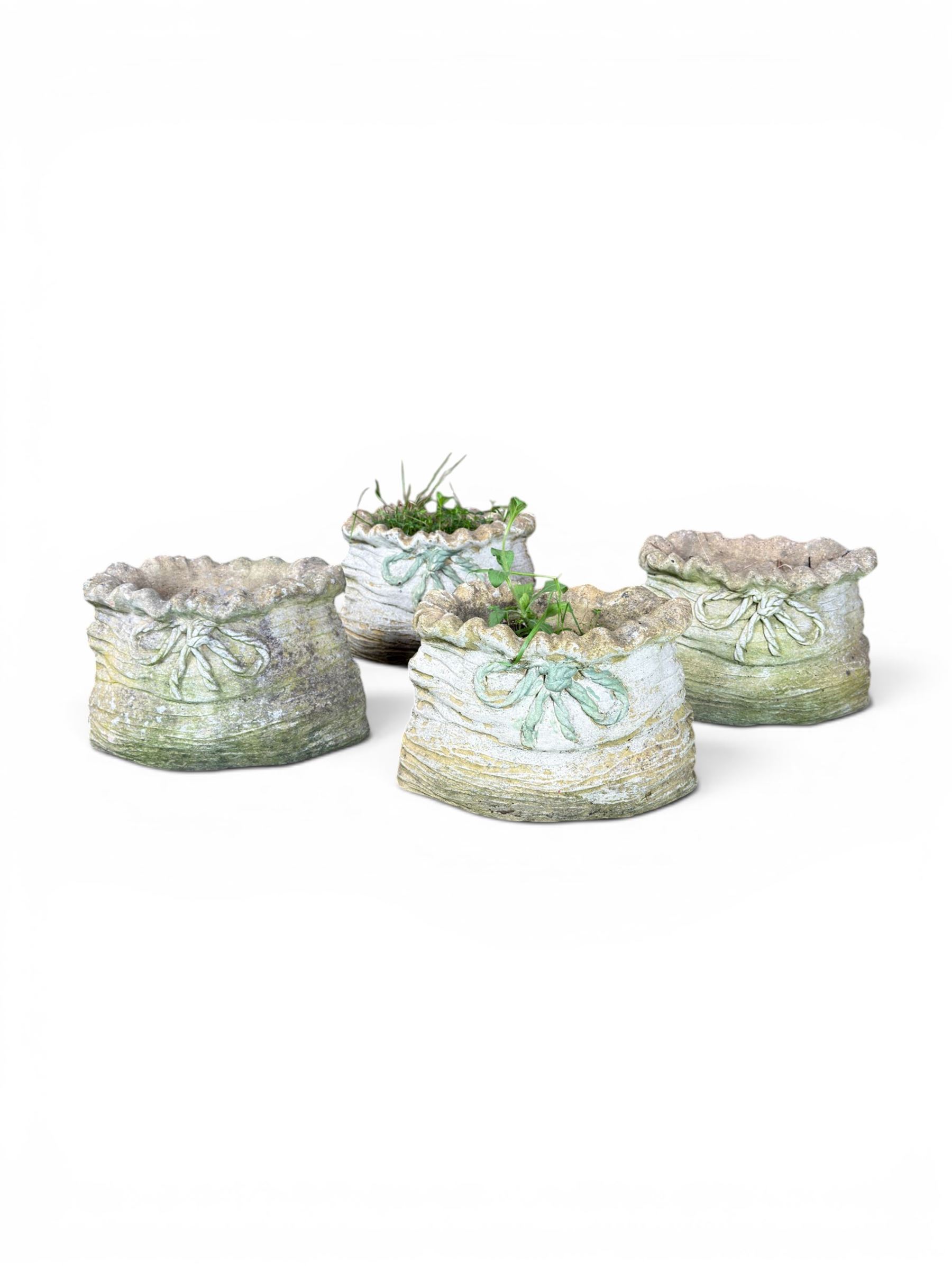 Four cast stone garden planters in the form of ribbon tied planting sacks