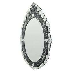 20th century Venetian style oval mirror, the central mirror plate enclosed by an ebonised border decorated with engraved floral trails and dotted reserves, the outer edge applied with shaped and etched glass leaves and scrolling foliage