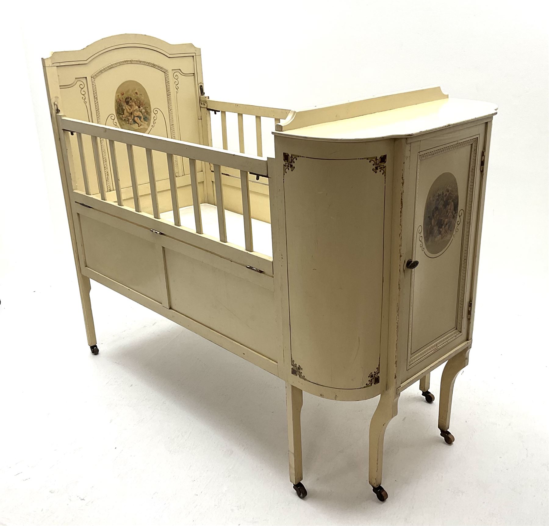 Early 20th century child’s cot, cream painted with applied oval putti