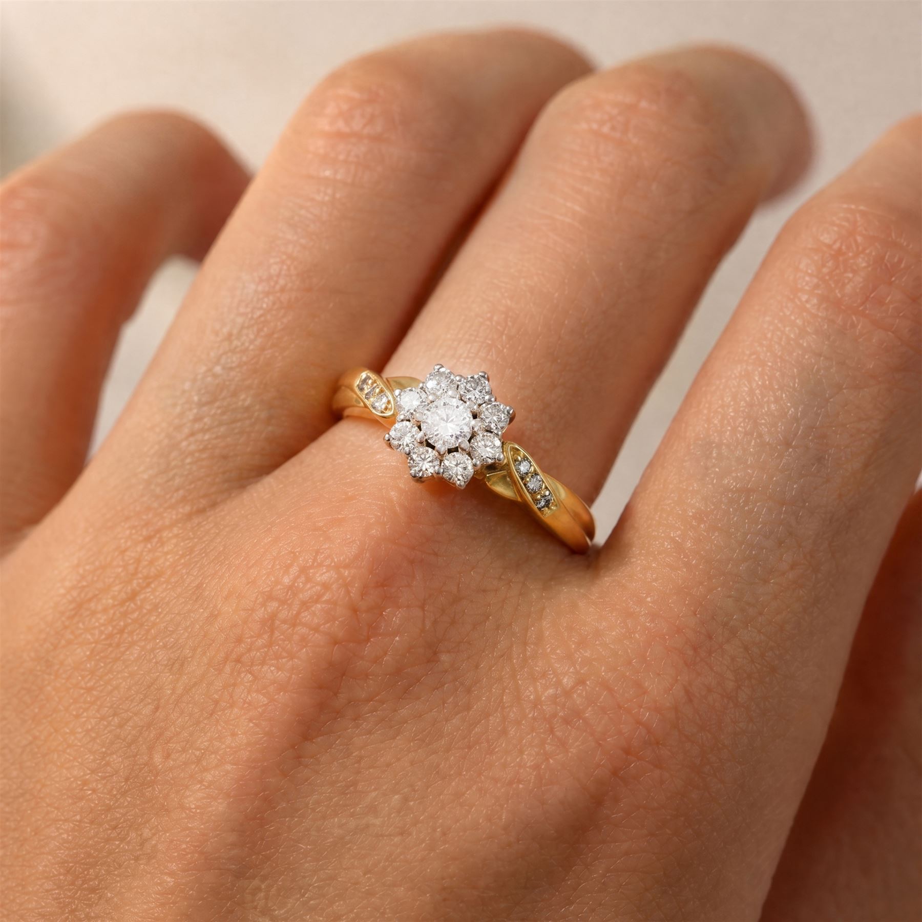 18ct gold diamond flower head cluster ring, set with nine round brilliant cut diamonds, with diamond set shoulders, London 1991, total diamond weight approx 0.40 carat