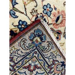 Persian ivory and peach ground rug, the ivory ground field with peach medallion and indigo spandrels, decorated with scrolled foliage and stylised floral motifs, the guarded border with signature panels decorated with flowers and birds with trailing branches