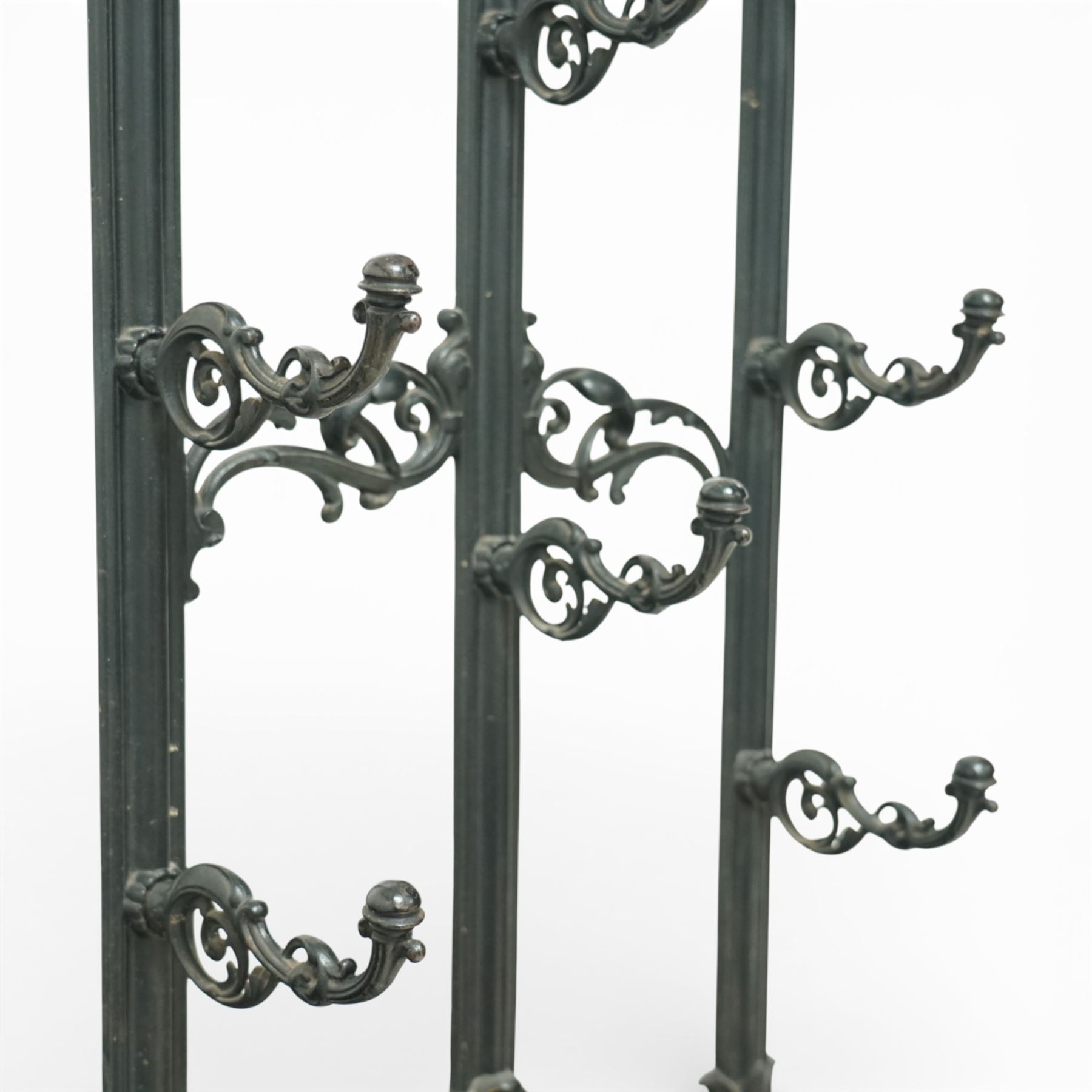 Late 19th century cast iron stick stand, the arched back with scrolling foliate decoration, fitted with multiple hooks, the lower section with pierced panels centred by a radiating sunburst motif, raised on a rectangular drip tray base