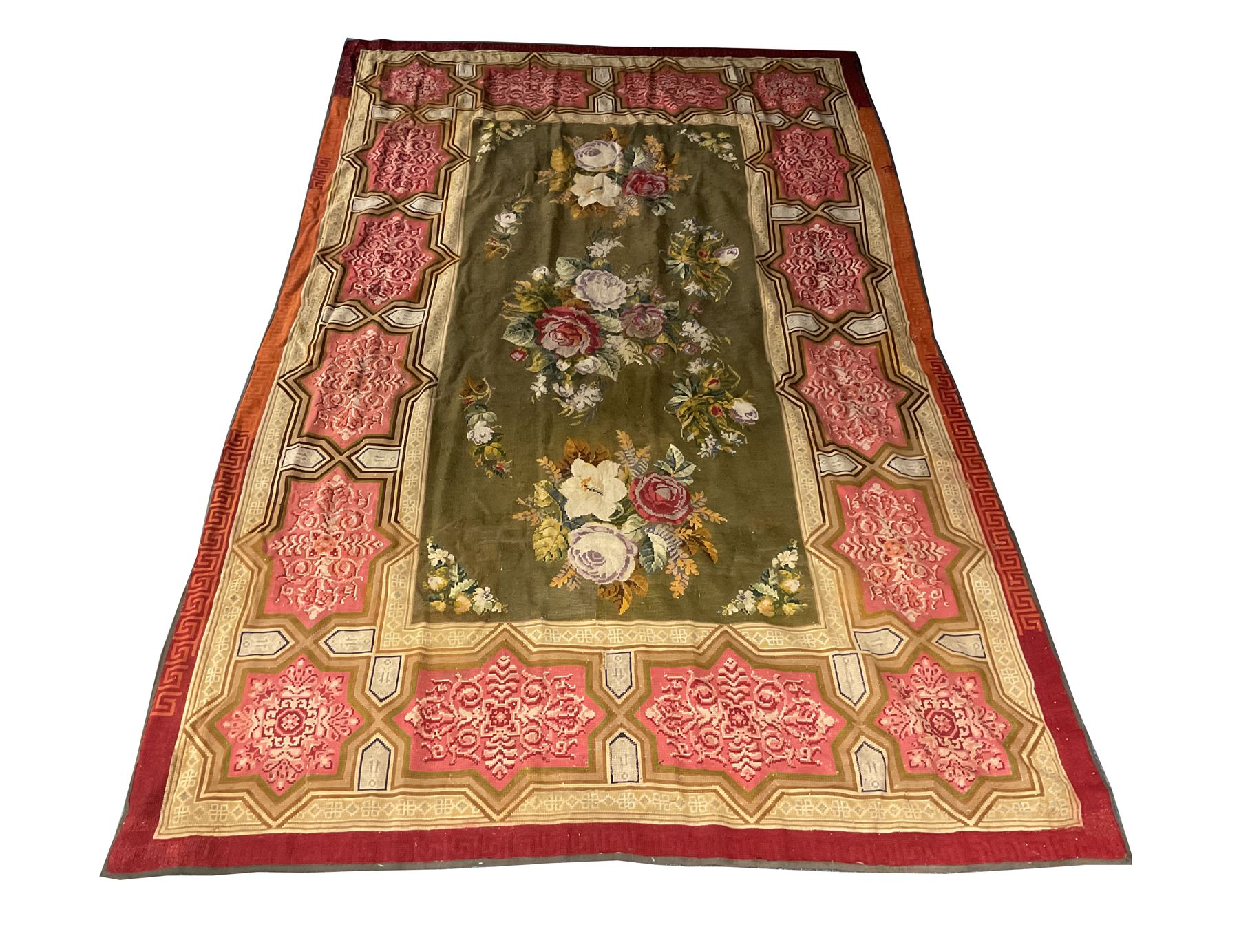 Needlework rug, green ground field decorated with flowers, the border decorated with a series of geometric panels with scroll and anthemion decoration, Greek key outer border 