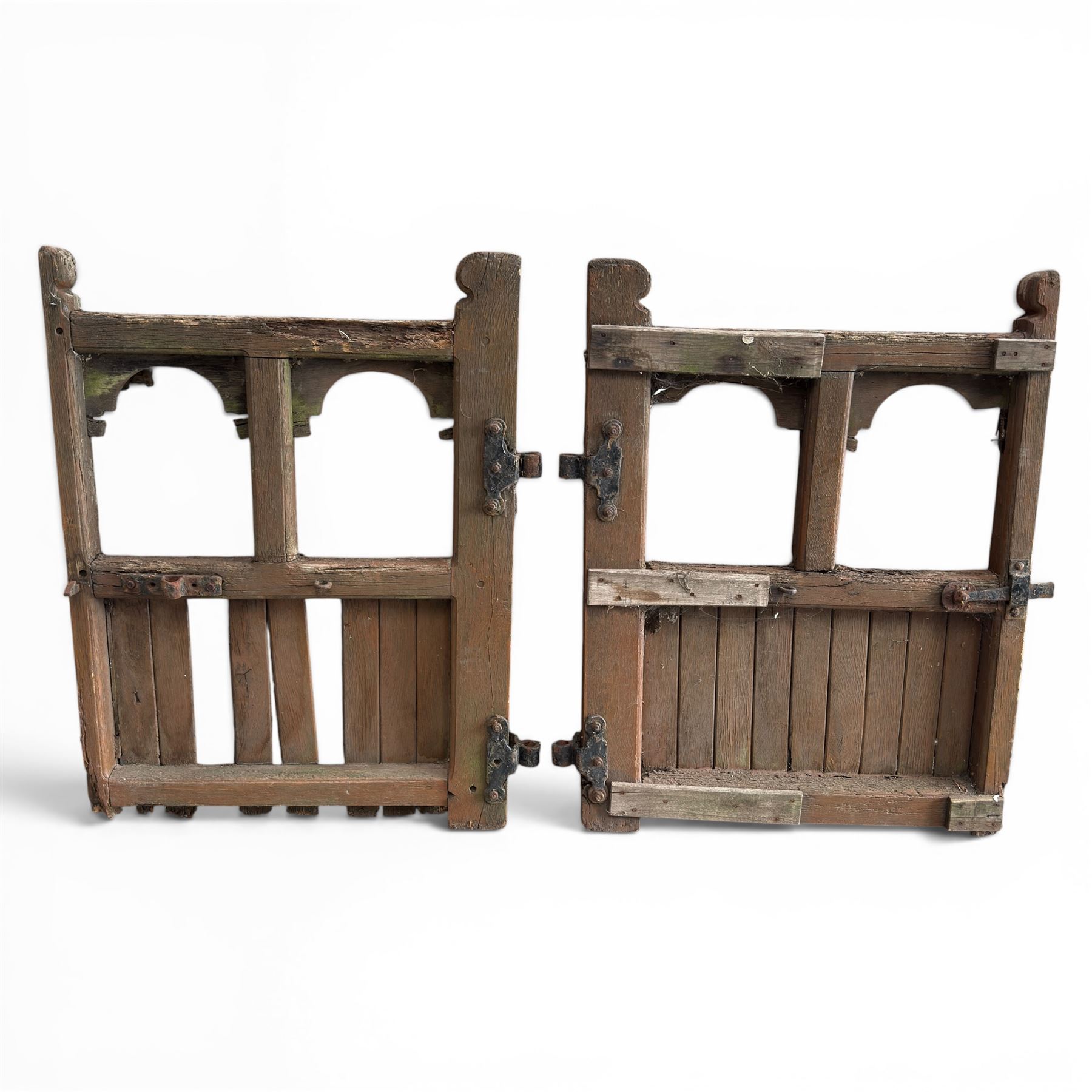Pair of 19th century weathered wooden ecclesiastical church gates, the cresting rail over four pierced arches with slatted lower section, fitted with heavy cast iron hinges, latch and fittings