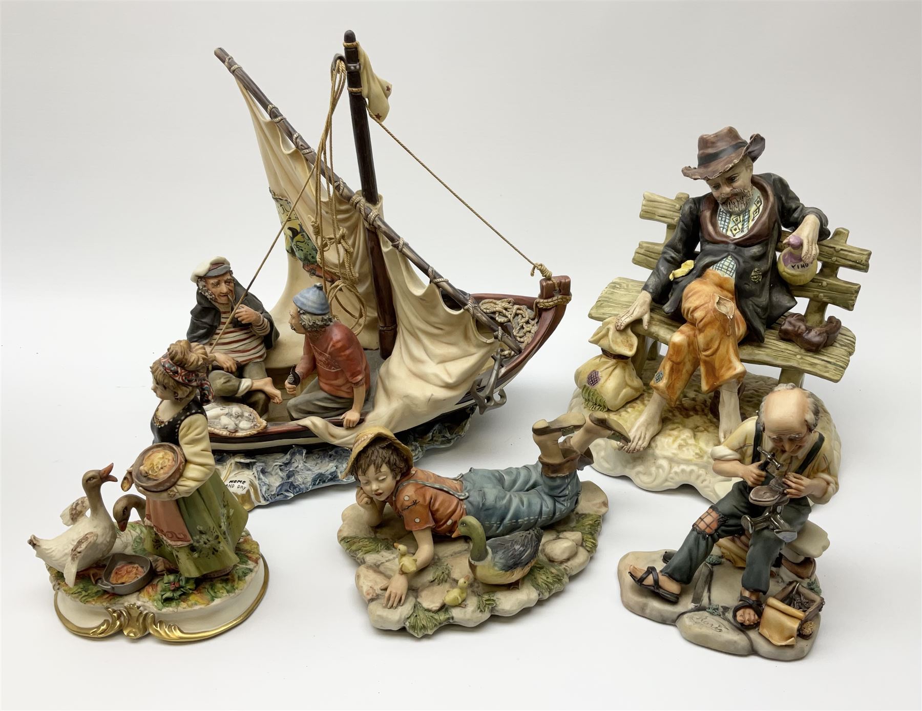 Collection of Capodimonte figures, comprising 'Home and Dry' H33.5cm, girl feeding geese H19cm, cobbler H17cm, boy lying down H11cm, and a Naples figure of man on a bench H27cm.   