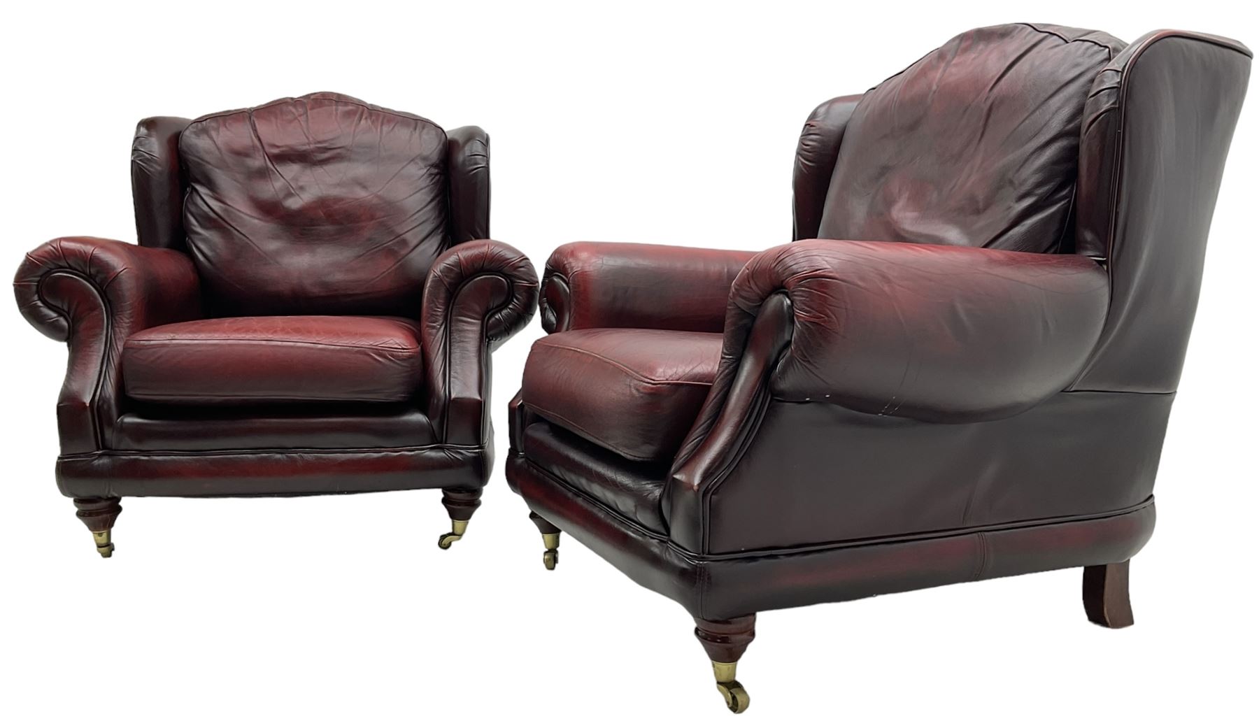 Thomas Lloyd - three-piece lounge suite, comprising of traditional shape two seat sofa (W190cm H80cm) and a pair of wingback armchairs (W100cm H91cm), each with rolled arms over turned supports with brass castors, upholstered in oxblood red leather