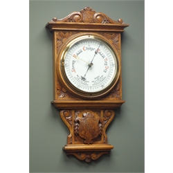  Early 20th century oak case aneroid barometer, carved scrolls and floral spandrels, with centre coat of arms crest, circular white enamel dial, H105cm  