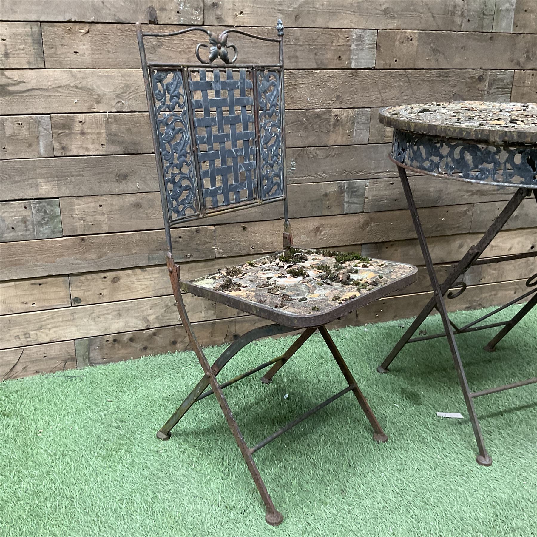 Circular metal garden table with tile top and matching chair, weathered