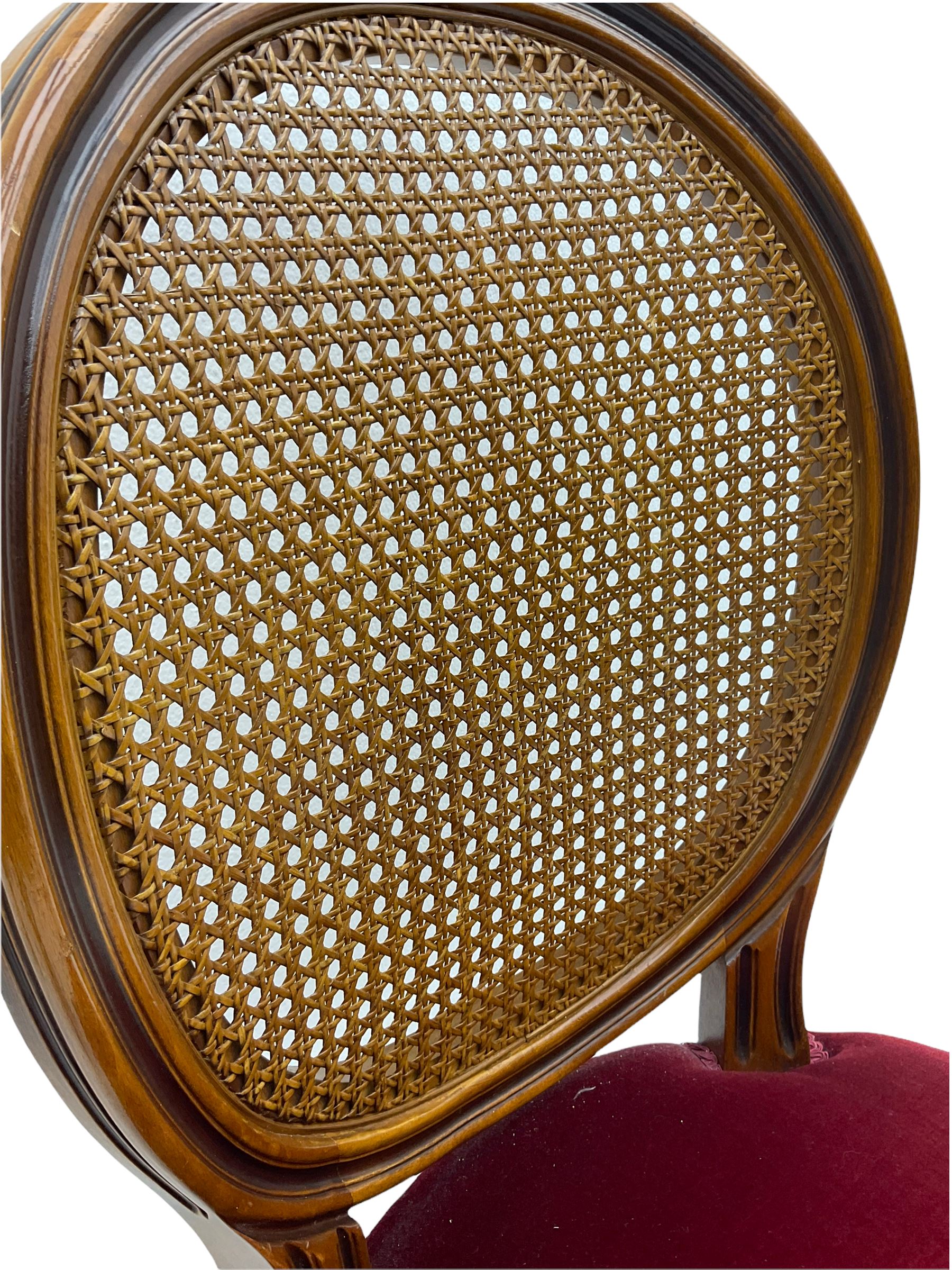 Set six French style walnut finish dining chairs, oval cane bergere backs over serpentine seats upholstered in red, flower head carved fluted supports