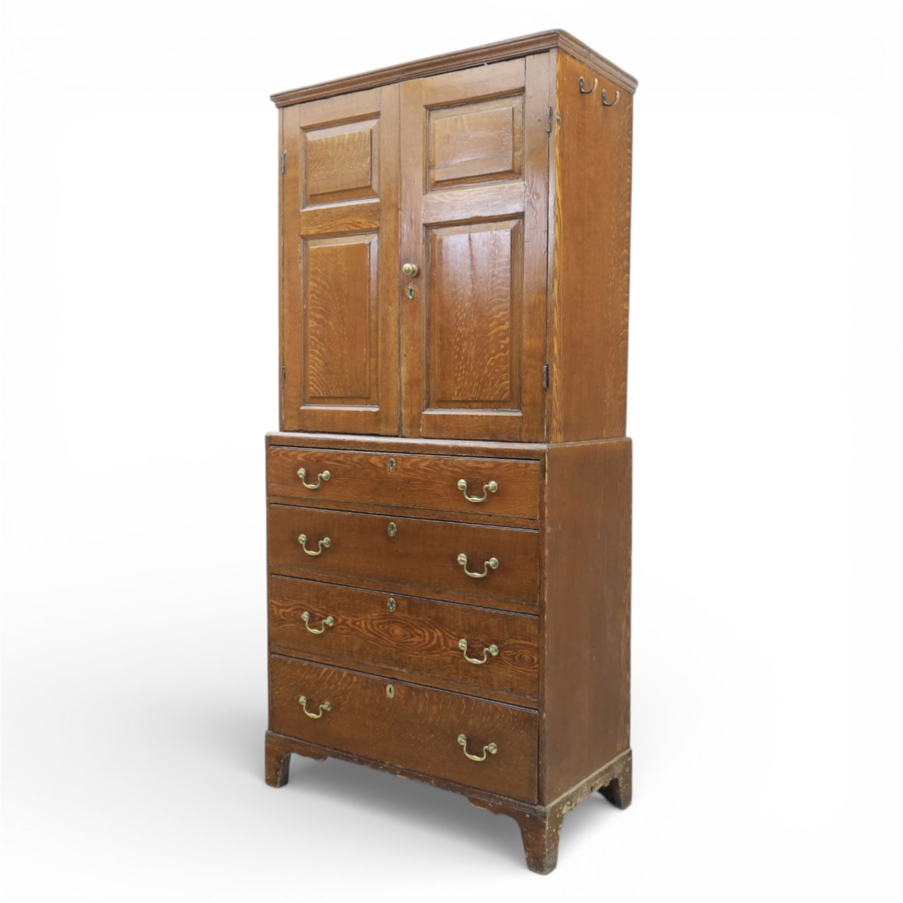 18th century oak press cupboard on chest, the moulded cornice above a pair of fielded panel doors enclosing shelved interior, the base fitted with four long graduated drawers with brass swan neck handles and shaped escutcheons, raised on bracket feet