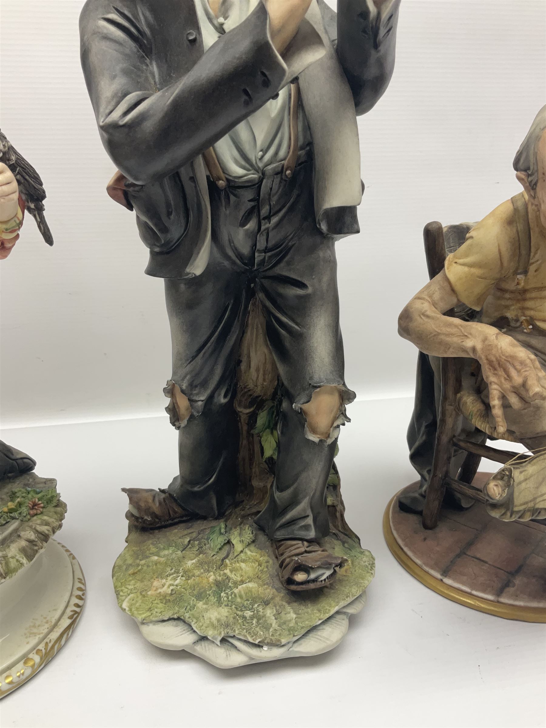 Three Capodimonte figures, to include The Kind Heart Man, modelled by Cortese as a tramp with two doves, The Young Falconer by Maria Angela and another modelled as a tramp darning his socks, all with printed marks, tallest H39cm