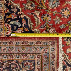 Persian Kashan carpet, the field in rich rust tone centred by an ivory and blue medallion with palmette extensions, surrounded by intricate foliate arabesques and stylised blooms, within triple floral borders incorporating palmettes and interlaced tendrils, woven in the region of Kashan