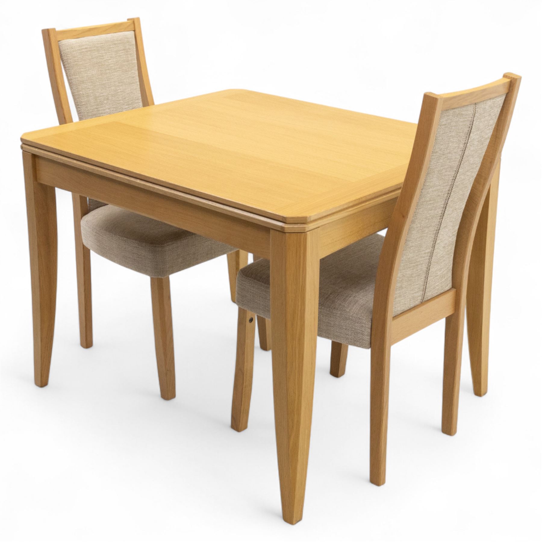 Ercol - light oak ‘Artisan’ rectangular dining table with chamfered top extending fold over top and tapered legs, together with two matching high back dining chairs upholstered in textured beige fabric (Chairs H 98cm, W 47cm, D 52cm)