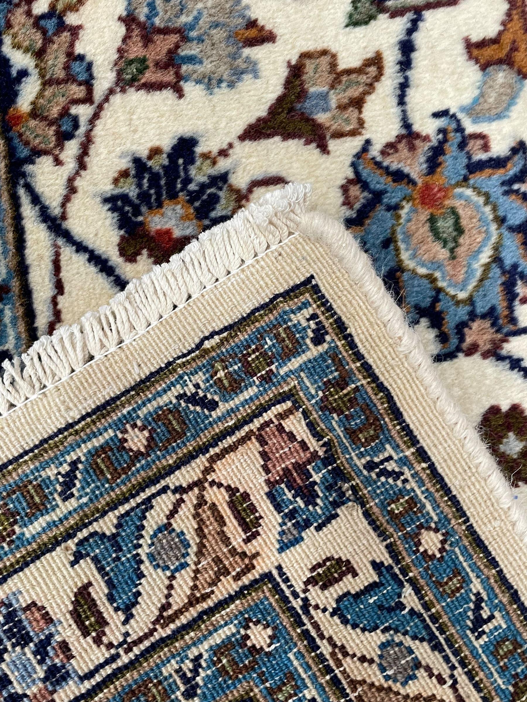 Persian Kashan ivory ground rug, the central medallion surrounded by an arrangement of palmettes united by scrolling leafy branches, peach ground main border decorated with trailing leaf and stylised plant motifs, floral pattern guard stripes 