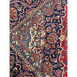 Central Persian crimson ground Kashan carpet, shaped floral medallion surrounded by trailing foliate branch and stylised plant motifs, repeating scrolling border decorated with further floral motifs