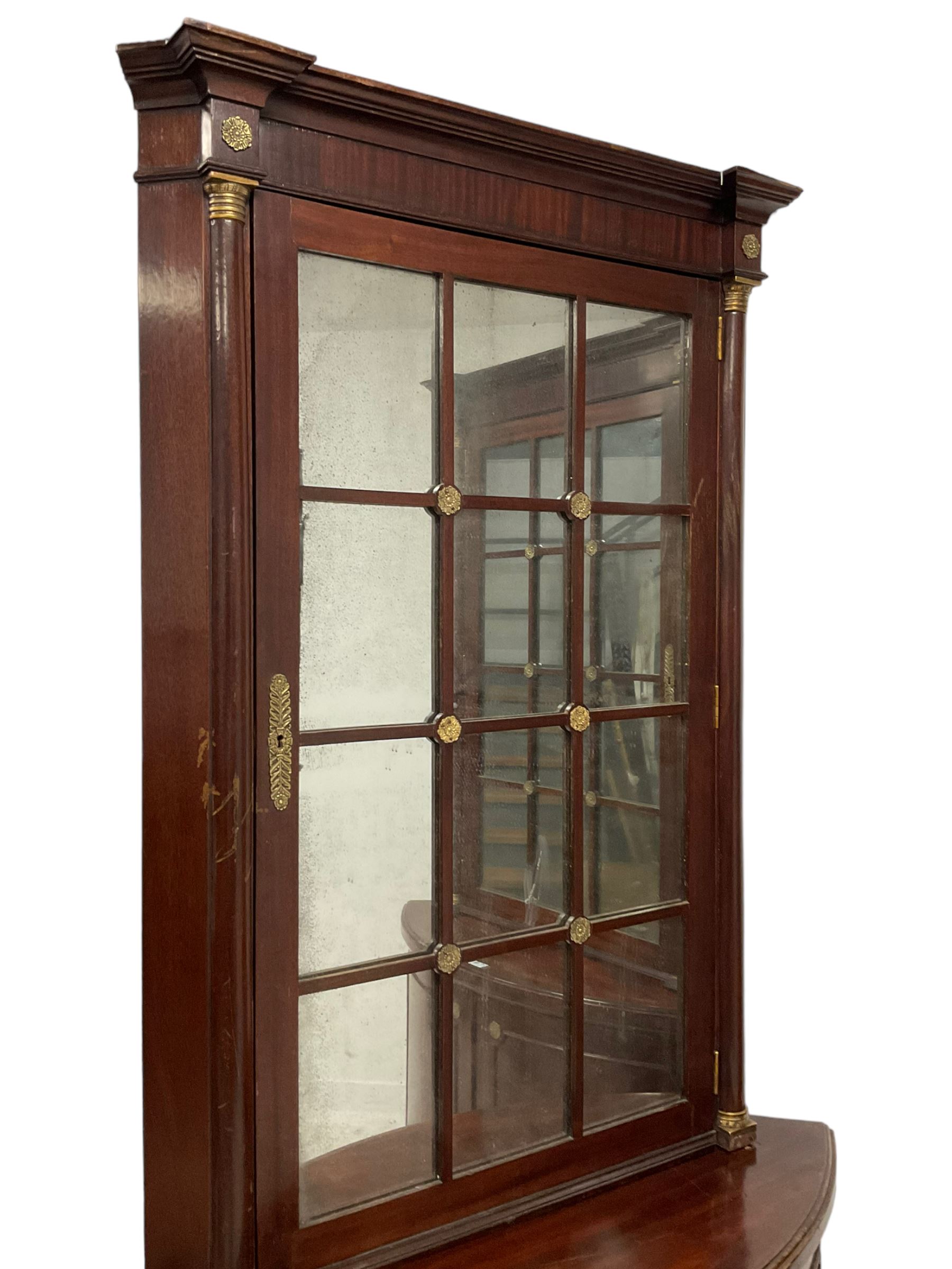 Pair of French Empire design corner cabinets, the straight-front upper section with canted corners and applied half-column pilasters, enclosed by mirror glazed door, the bow-front lower section enclosed by two doors with applied mouldings, mounted by cast metal floral rosettes, skirted base with cast gilt metal hairy paw brass feet