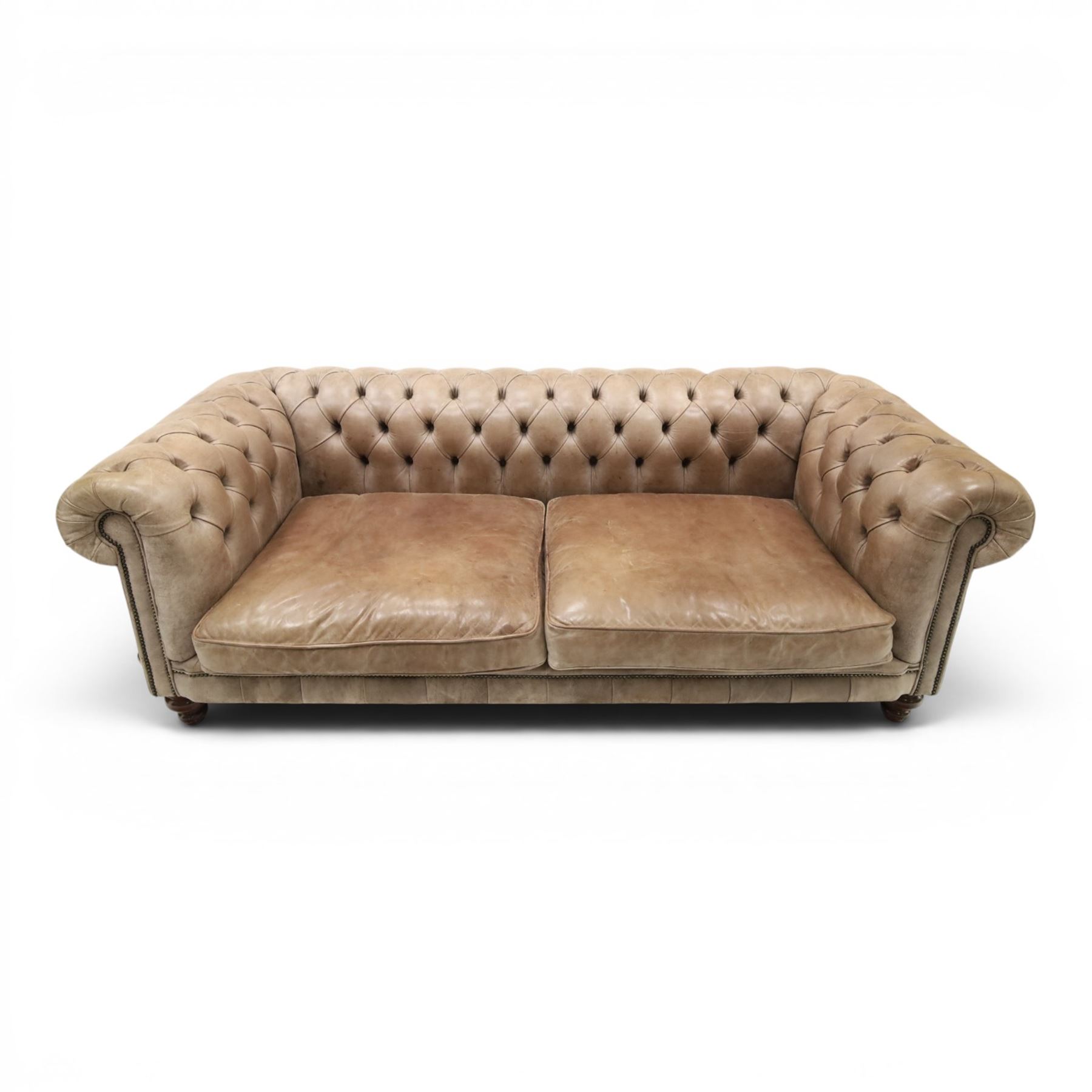 Distinctive Chesterfield - Chesterfield upholstered in taupe leather, deep button back and arms, loose seat cushions, raised on dark stained supports 