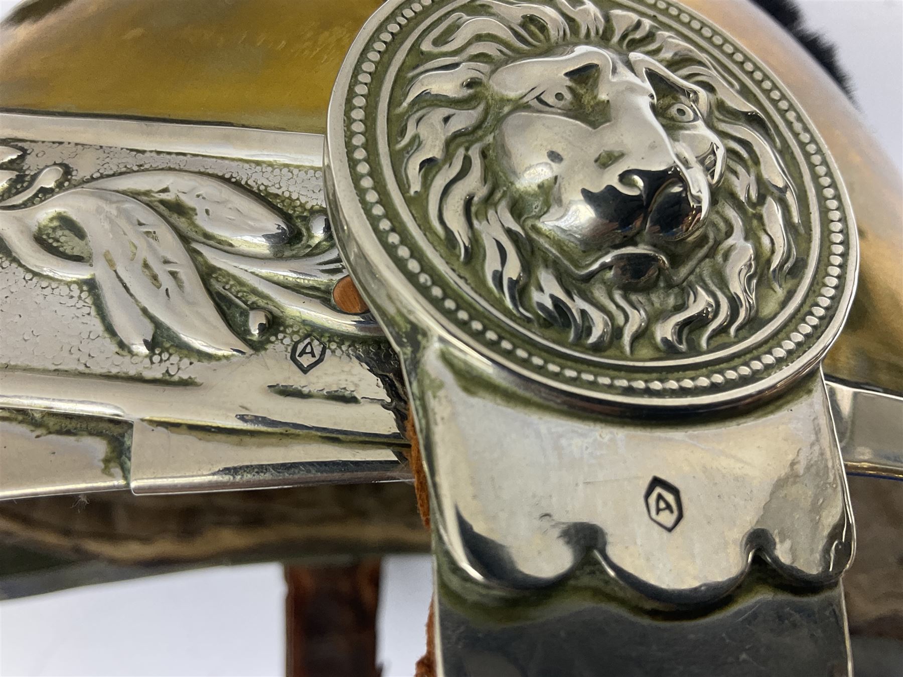 Early 20th century French mounted gendarme's helmet, brass with nickel-silver mountings, broad band embossed with fused grenade, high comb with the face of the gorgon Medusa at the peak and with a black horse hair crest, plume socket at the left, leather-backed nickel-silver chin scales with lion mask mounts.