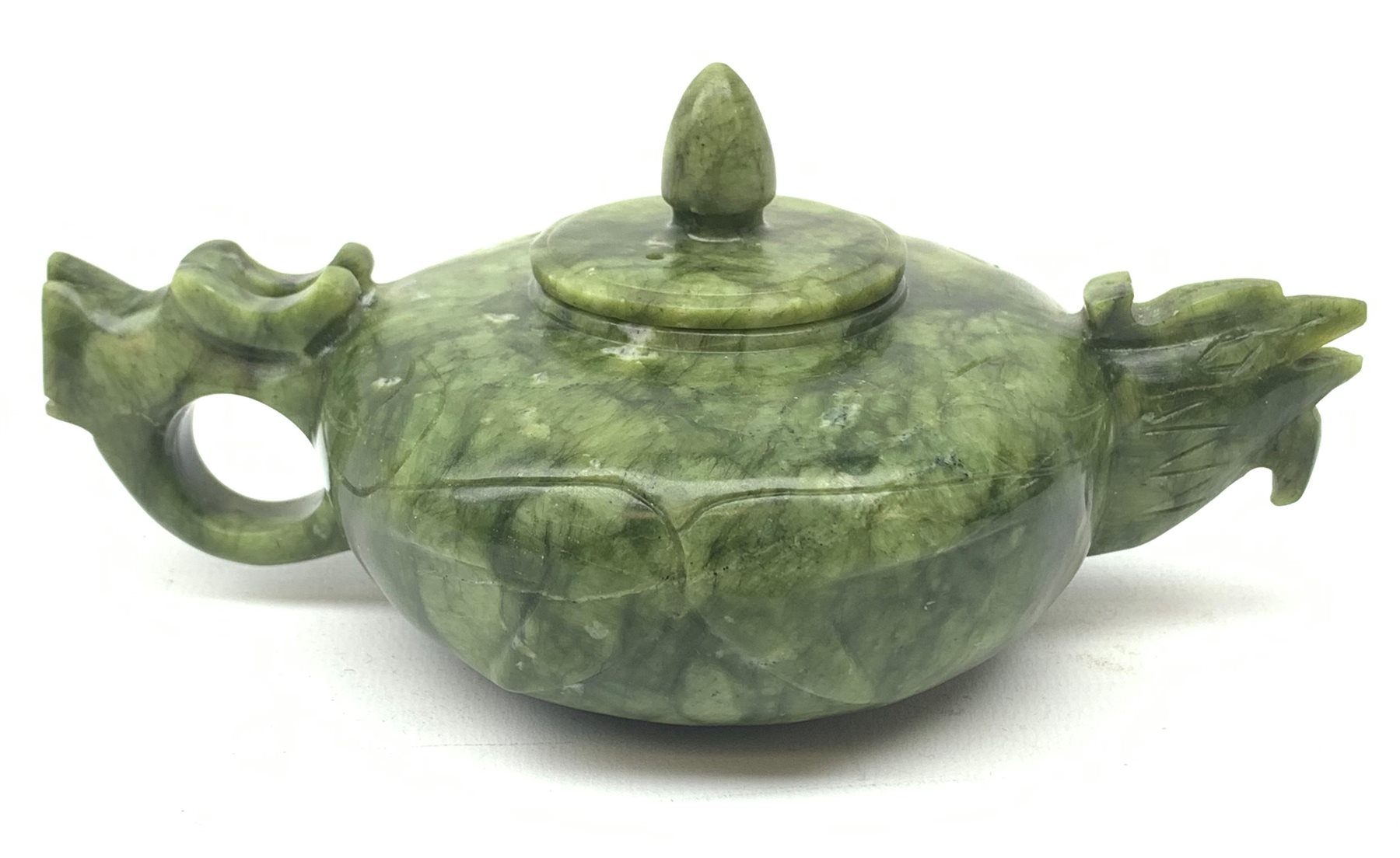 A carved jade teapot, the spout modelled as the head of a bird, the handle modelled as a stylised dragons head, H7.5cm. 