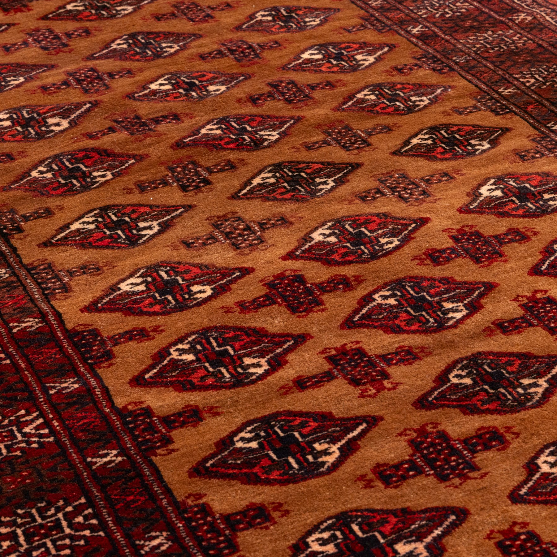 Afghan Bokhara dark amber and terracotta ground rug, decorated with Hac and Gul motifs  within multiple geometric guard bands