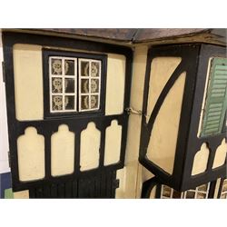 Large Tri-ang No.93 doll`s house in the 'Stockbroker's Range' c1935; two-storey double-fronted Tudor design, half timbered gables, two-storey bay windows, cream and mock shrubbery to front, opening metal framed windows with green shutters, red simulated tiled roof with chimney, integral garage with opening doors, front elevation has four hinged doors opening to reveal two bedrooms with fire places, living room, bathroom and kitchen with built in dresser and sink, entrance hall and staircase, side entrance with porch and seat and sun dial over on chimney stack; some wiring for electrical lighting; metal Tri-ang Toys disc verso; comprehensively furnished H66cm L117cm D43cm