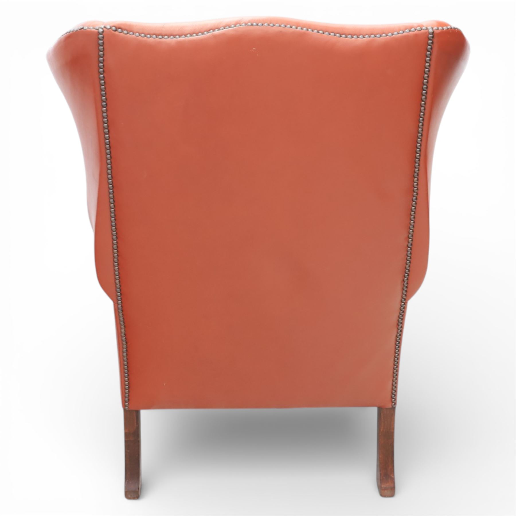 Georgian design red leather wingback armchair, with shaped back and scrolled arms, and close brass studded trim, upon cabriole front legs with claw and ball feet