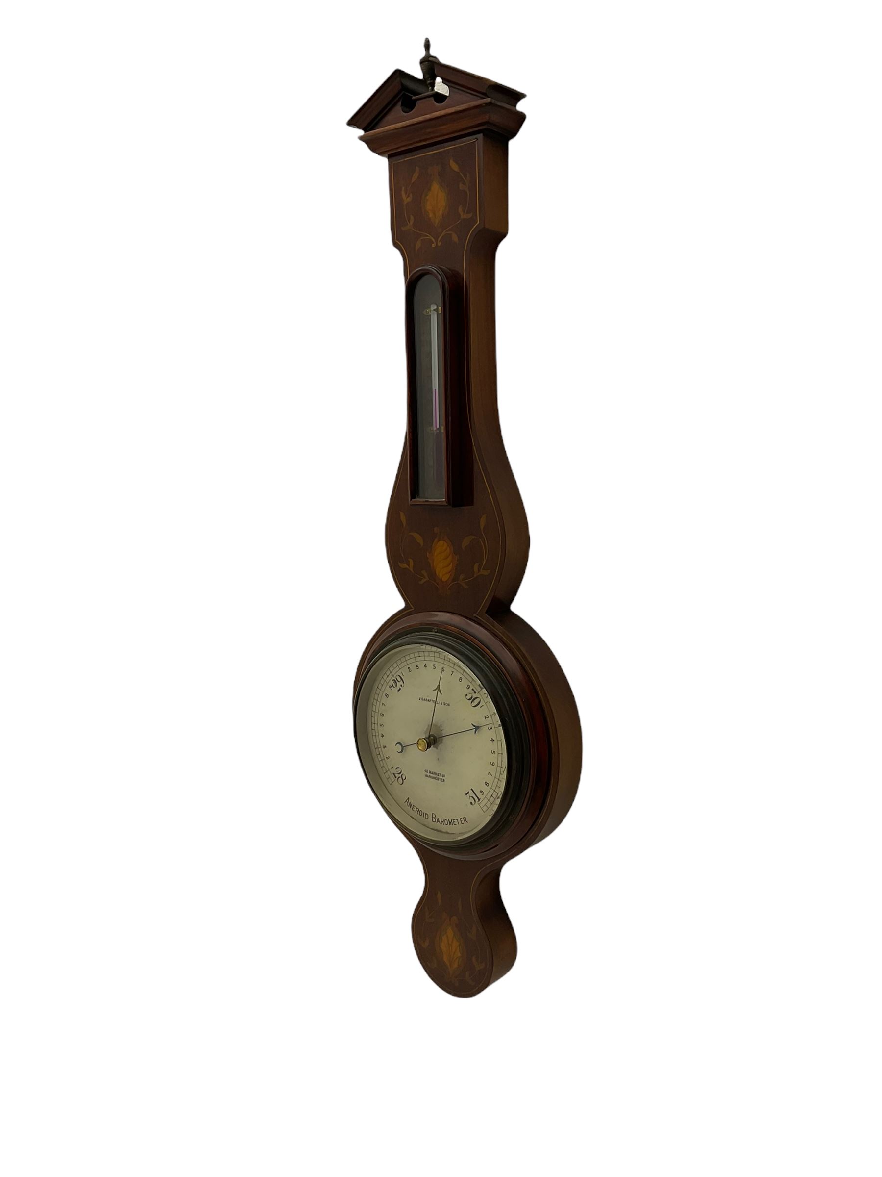 A compact Edwardian Aneroid barometer in a  Regency “Sheraton style”case, broken pediment with finial and rounded base, mahogany veneered with satinwood stringing to the edge and panels of coloured and shaded conch shell and leaf inlay enclosed within entwined leaves, with a six inch dial recording barometric air pressure from 28 to 31 inches in fifths of an inch, steel indicating hand and brass recording hand, dial inscribed “J Casartelli & Son, 43 Market Street, Manchester”, with a flat bevelled glass and brass bezel, glazed arched topped thermometer box with a spirit thermometer and silvered register recording the temperature in degrees Fahrenheit.
*J Carsatelli & Son (1896-1925) A partnership between Joseph Lewis and his son Joseph Henry. The elder Joseph died in 1900 and the son carried on the business until his death in 1925.  
