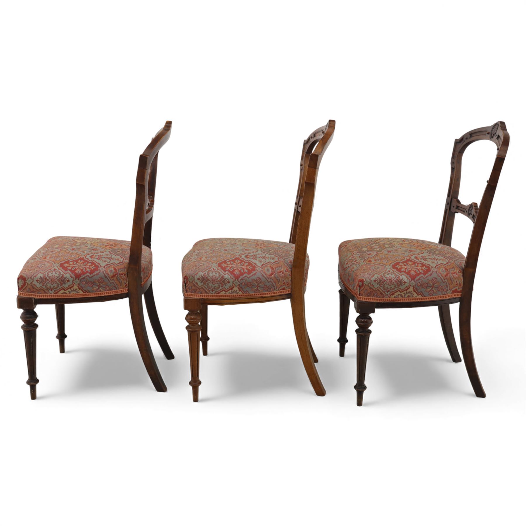 Set of six late Victorian mahogany dining chairs, the shaped top rails carved with anthemion motifs, above pierced splats, floral and geometric fabric seat, on turned and fluted front legs
