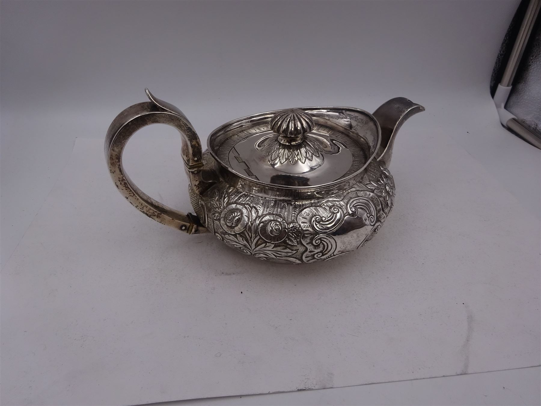 George III Irish silver teapot, of squat circular form, the body with repousse and chased floral and C scroll decoration, with capped C handle and ivory insulators, engraved to base 'Presented to Troop Sergeant Major John Percival, of the 4th Dragoon Guards by Alex D. Tait, Esq, late Captain in that corps as a mark of approbation of his steady and upright conduct when Sergeant Major of his Troop, Dublin, June 2nd 1843', hallmarked William Law, Dublin 1817, H12.5cm, This item has been registered for sale under Section 10 of the APHA Ivory Act