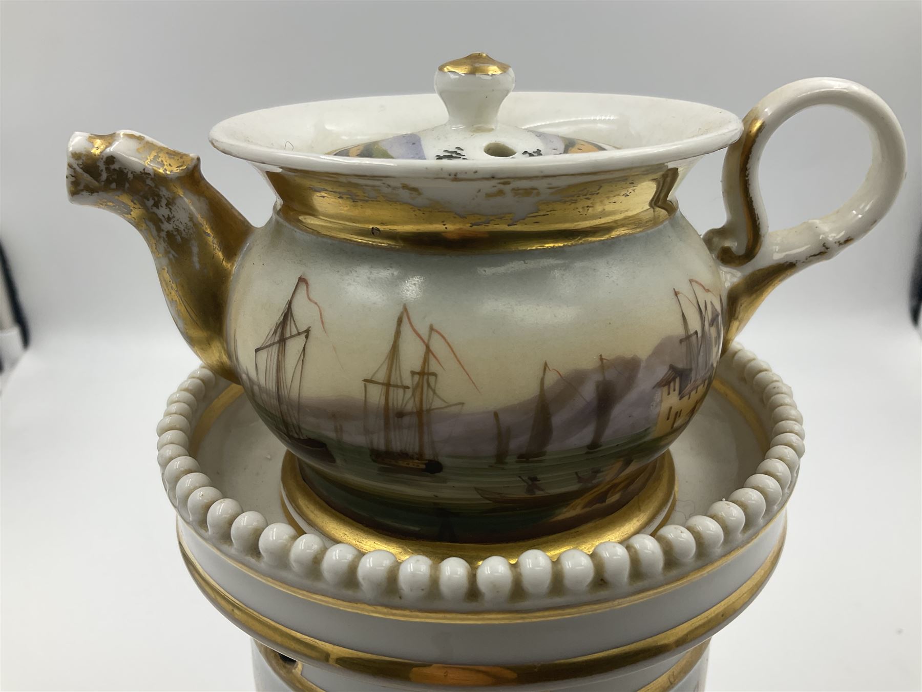 Two 19th century continental teapots and warmers, each teapot upon a cylindrical warming base, hand printed with seascapes, largest H22cm 