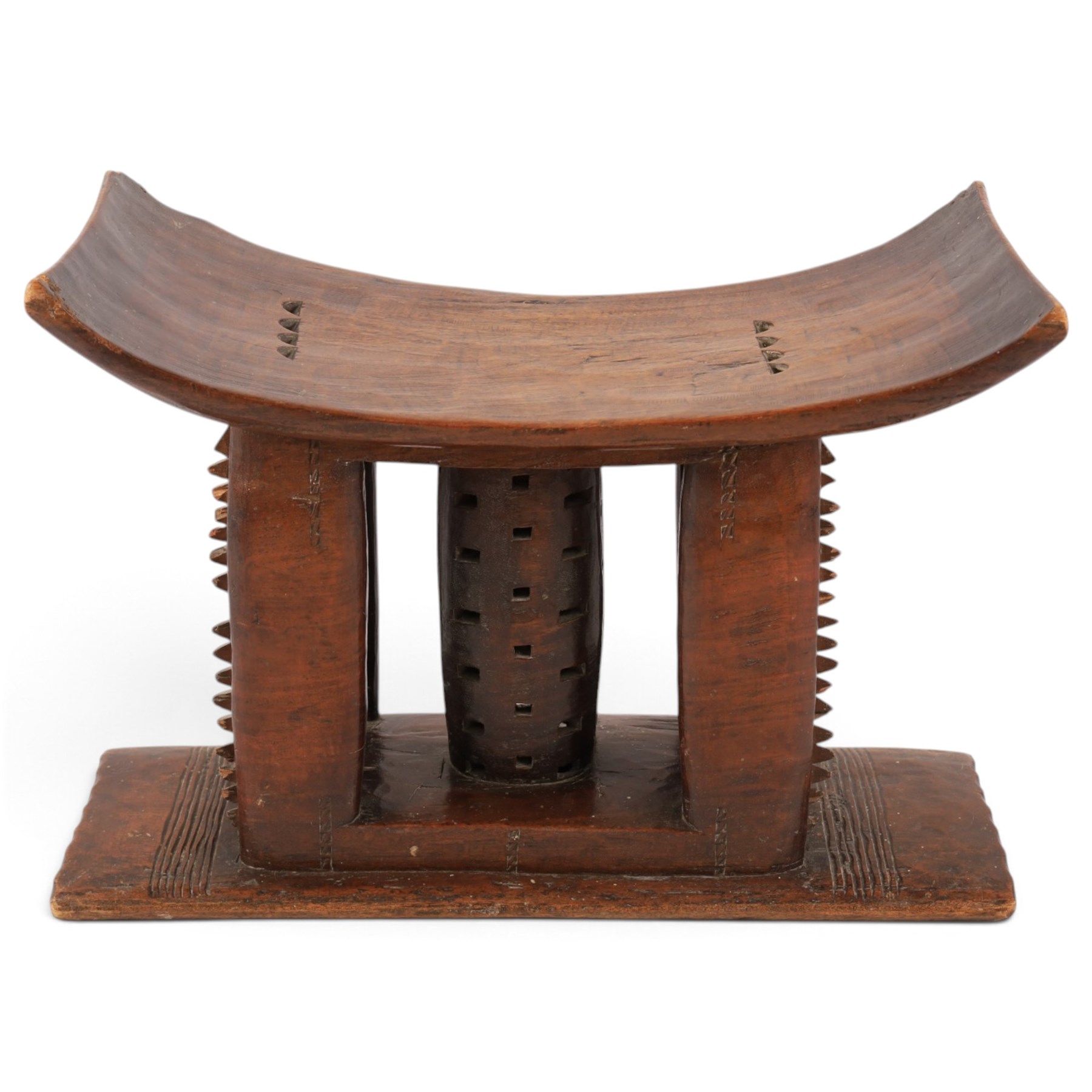 African carved hardwood headrest, having flared edges, raised on a stepped plinth base with further carved detailing, H34cm